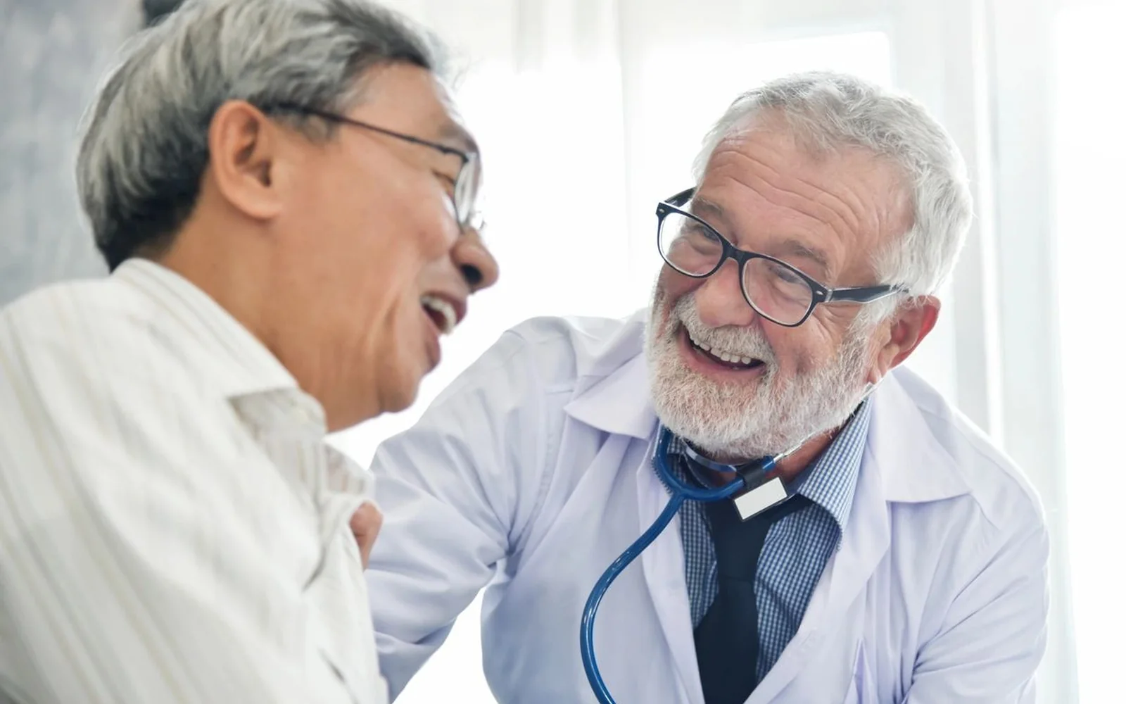 Doctor laughing with an older patient during a visit